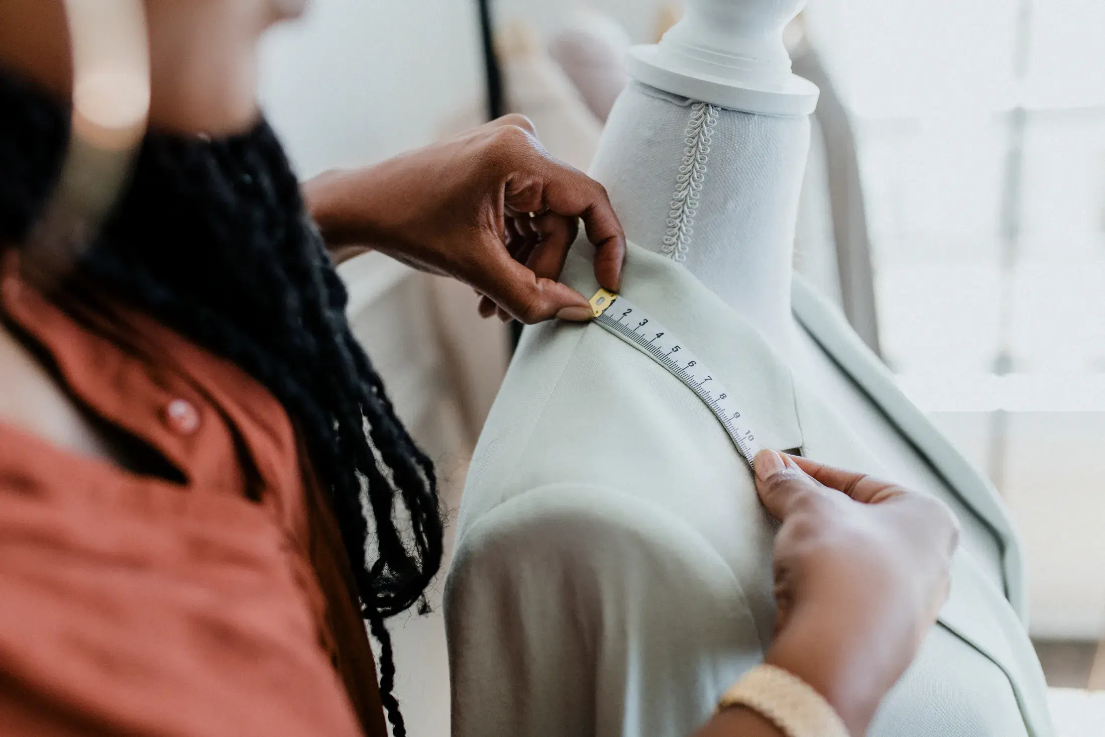 A tailor taking measurements from a finished jacket